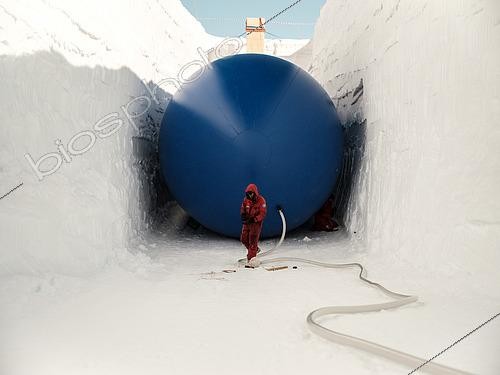 Biosphoto | 2592800 | Deux techniciens installent et gonflent un ballon cylindrique de 5 mètres de diamètre et 35 mètres de longueur. Ce ballon sert de moule à la neige qui sera déposée dessus. Une fois dégonflé, on obtient une cave assez spacieuse pour y stocker véhicules et équipements divers. La structure beige et orange au fond est l'escalier de secours. Station de recherche scientifique Antarctique Concordia, plateau du Dôme C, Antarctique de l’Est/oriental. | &copy; Armand Patoir / Biosphoto