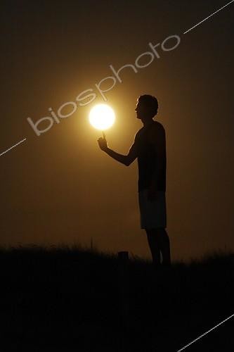 Biosphoto | 1159859 | Person giving the impression of playing basket with the Moon ; A basketball player spins the Full Moon at the end of his finger | &copy; Laurent Laveder / Biosphoto