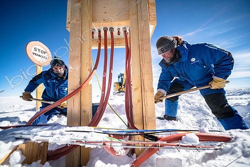 Biosphoto | 2592781 | Two technicians finish digging a trench in the snow with shovels, in front of an outdoor electrical box. In summer, a team of around 25 technicians from various trades carry out various maintenance tasks at the resort. This includes the electrical distribution network, which is put to the test by the cold and temperature variations, and whose needs, particularly for scientific installations, are constantly increasing. Manual labor on Concordia is particularly demanding, obviously because of the cold, but also because of the lack of oxygen. Concordia Antarctic Research Station, Dome C plateau, East Antarctica. | &copy; Armand Patoir / Biosphoto