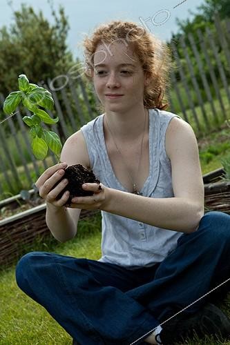 Biosphoto | 891086 | Young girl with a seedling of basil in a garden | &copy; Philippe Giraud / Biosphoto